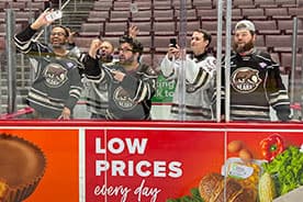 Five fans in the penalty box during pre game warm up.